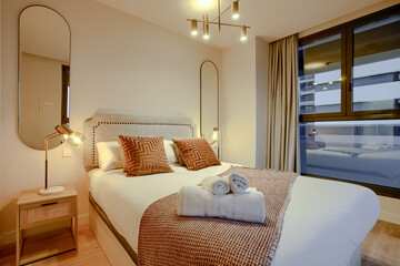 A double bedroom with contemporary decoration, two mirrors on the wall, gold accessories and lamps...