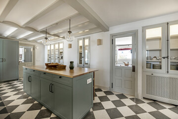 large kitchen with checkerboard floor, built-in cabinets with cupboards, a central island with...