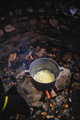 A hearty pot of food bubbling atop a crackling fire, creating a scene of warmth and comfort in the...