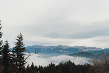 A breathtaking scene unfolds as low lying clouds gracefully embrace a towering mountain range,...