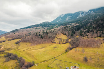 A captivating aerial view of a serene farm nestled in the majestic mountains, showcasing lush fields, grazing livestock, and winding pathways