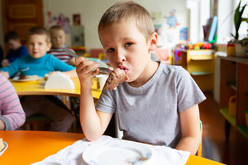 A little boy is eating in kindergarten. Nutrition for small children.