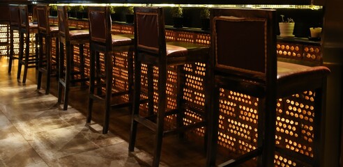 Wooden bar stools wood tall chairs at bar counter with illuminated decorative bricks