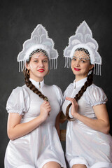 Two Russian Girls in a Snow Maiden costume posing on a gray background.