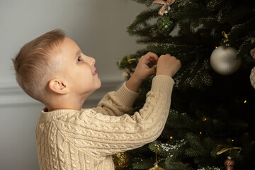 A little boy decorates a Christmas tree.