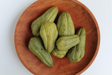 Steamed fruit of small Chayote or Sicyos edule, on wooden plate, isolated on white background, flat lay or top view