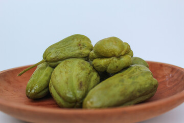 Steamed fruit of small Chayote or Sicyos edule, on wooden plate, isolated on white background