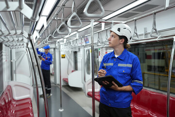 Electric train technician engineer checking controls system for security functions in maintenance infrastructure plant of sky train, public transportation vehicle,Teamwork management concept.