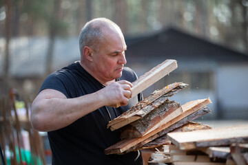 An elderly man prepares firewood for the winter.