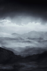 mysterious dark landscape with hills and mountains shrouded in fog