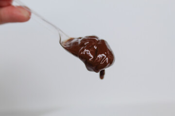 One spoon of melted dark chocolate, or chocolate spread, isolated on white background