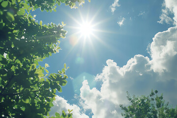 Obraz premium Bright sunlight shining through green leaves under a blue sky filled with fluffy clouds in a serene outdoor setting
