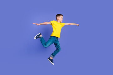 Obraz premium Full length photo of cheerful positive boy wear trendy yellow clothes have fun flight fly air isolated on violet color background