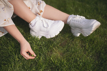 woman in sneakers touches her hands. Close-up cropped shot of unrecognizable young woman wearing...