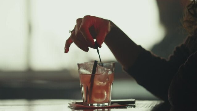 Woman stirring her cocktail at bar
