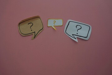 top view of of black question and exclamation mark on white speech bubble on a pink background.