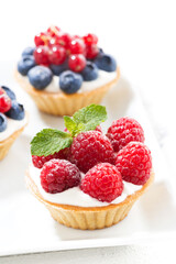 mini cakes with cream and fresh berries, vertical