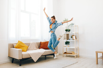 Joyful Woman Jumping with Music and Smiling on Sofa in Carefree Home