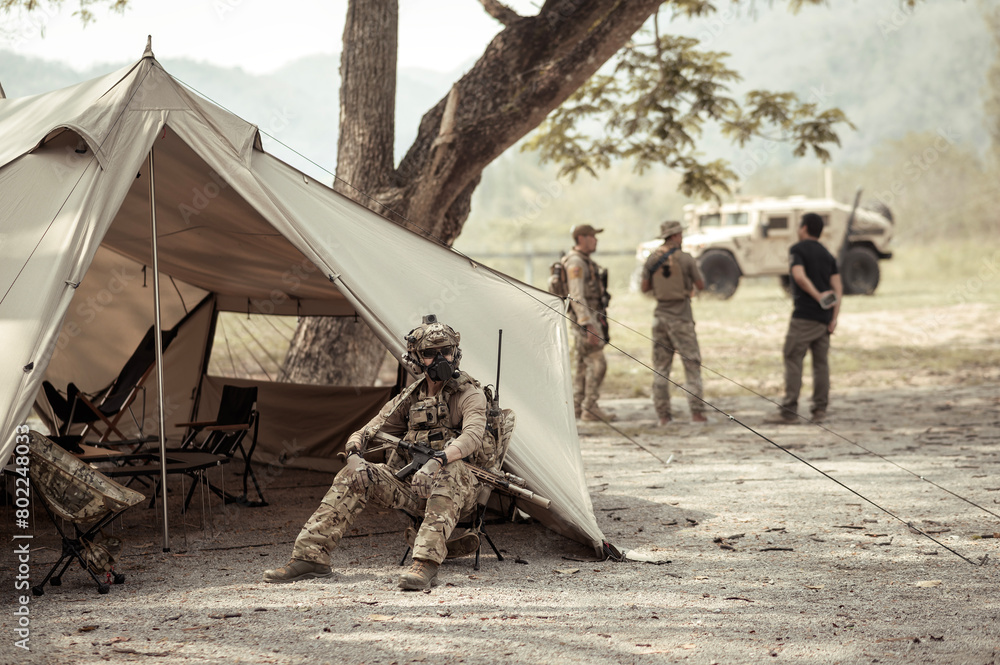 Wall mural Soldiers in camouflage uniforms planning on operation in the camp