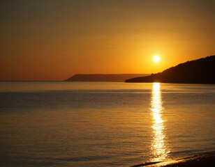 Fototapeta premium Peaceful orange sunset over the calm beach with mountains background in Mediterranean 