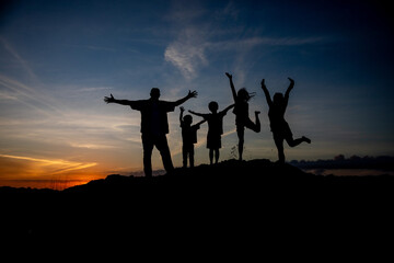 silhouette of a family with raised hands