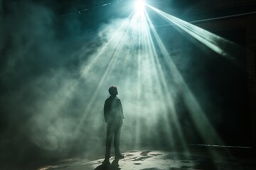 A lone figure is enveloped in mist under a powerful spotlight, suggesting themes of revelation, solitude, or introspection