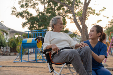 Young nurse and elderly asian senior woman on wheelchair, Asian careful caregiver and patient, ...