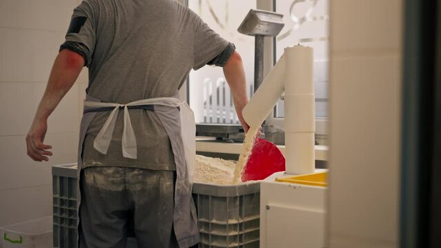 outline of a baker leveling the flour that is pouring in a container in professional kitchen