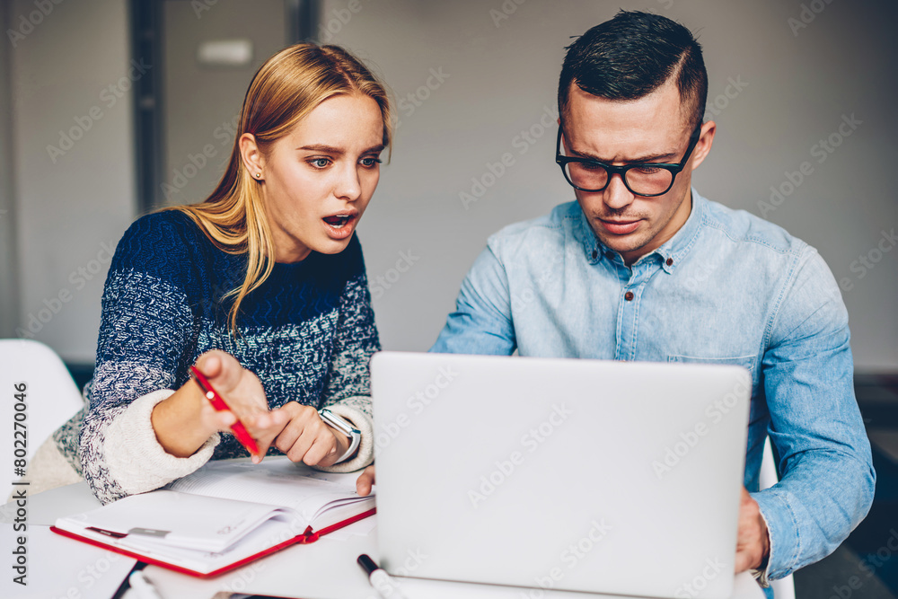 Poster shocked female employee worried about software fail while male colleague making installation on lapt
