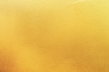 Gold wall texture background. Yellow shiny gold foil paint on wall surface with light reflection