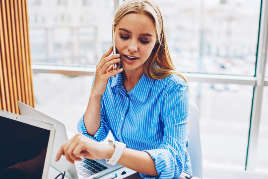Concentrated female manager having phone conversation checking time on wearable computer arranging meeting,businesswoman talking on telephone checking notification on modern digital smartwatch