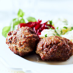Hamburger steaks with potatoes and fresh herbs on bright background. Close up.	