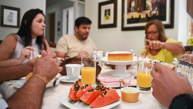 Fam&iacute;lia em casa sentada a mesa pra tomar caf&eacute; da manh&atilde;, reuni&atilde;o de fam&iacute;lia, fam&iacute;lia feliz comendo. Mesa de caf&eacute; da manha com frutas e p&atilde;o