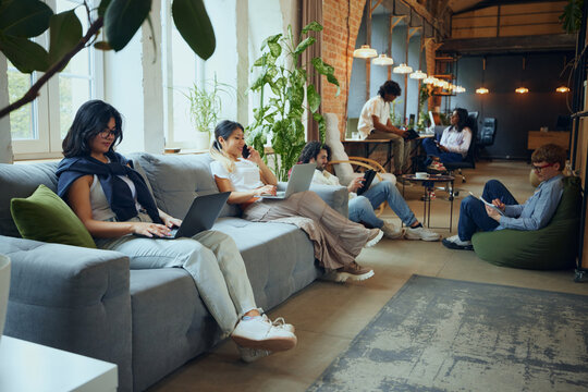 Creative business hub. Young multi ethnic people gathering in modern office for work and study, finishing own tasks in cozy but professional atmosphere. Business and education, co-working space