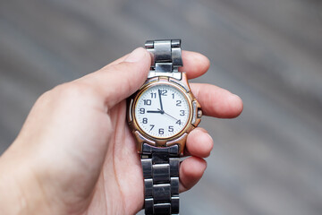 a person is holding a watch in their hand that shows the time