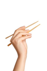 A woman's hand holds wooden chopsticks for sushi or rolls on a blank background.