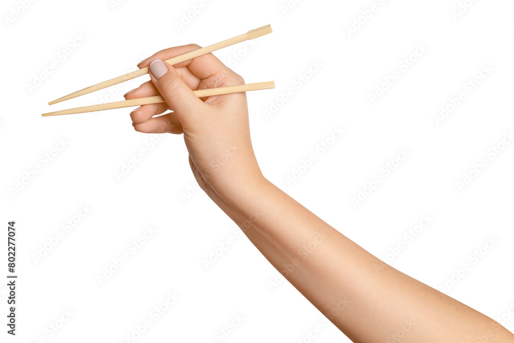 Wall mural a woman's hand holds wooden chopsticks for sushi or rolls on a blank background.