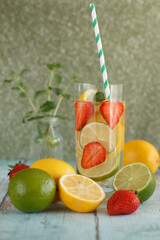 A glass of lemonade with lemon, lime and strawberries.