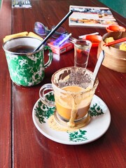 wooden table after lunch in a Chinese restaurant cluttered with coffee and milk tea glasses, cigarettes, chili sauce and dim sum steamers