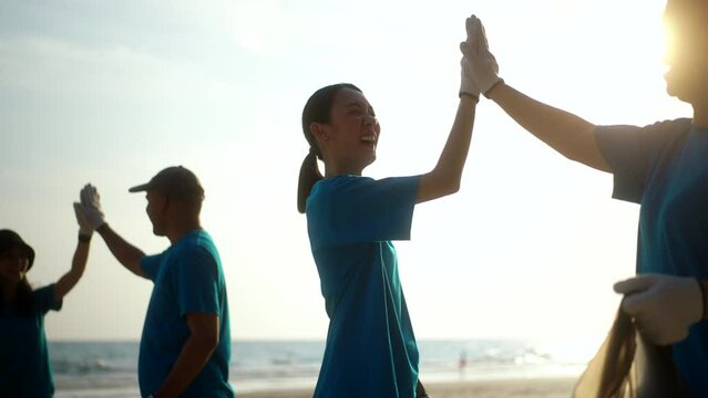 Teamwork moment of volunteer people group in volunteering charity activities cleaning up waste plastic on sand sea ocean beach . Corporate social responsibility and society activity for Environment.