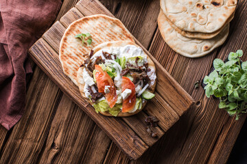 Greek gyros wrapped in pita breads on a wooden background