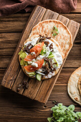 Greek gyros wrapped in pita breads on a wooden background