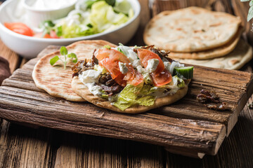 Greek gyros wrapped in pita breads on a wooden background