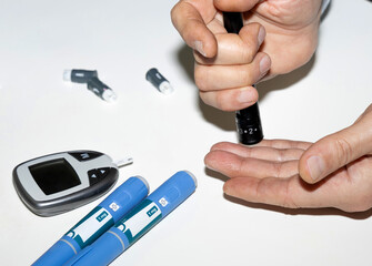 Diabetic man measuring blood sugar level. Blood test for diabetes and injection pen with Ozempic insulin.