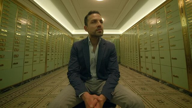 Businessman Sitting Inside Bank Safe Vault Room Watching People 