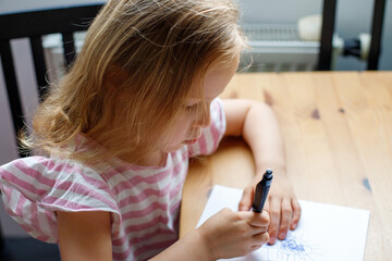 girl draws at home in the kitchen. child development, kindergarten, social and family