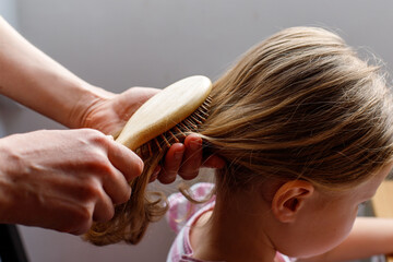 Close-up of a mom brushing her daughter's hair. baby hair care