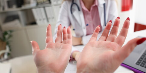 The woman listened to the diagnosis in the doctor office, spread his hands and says why