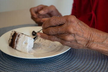 the hand of an old woman eating cake