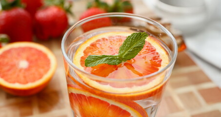 Red orange punch with green mint home made cocktail closeup on wood background